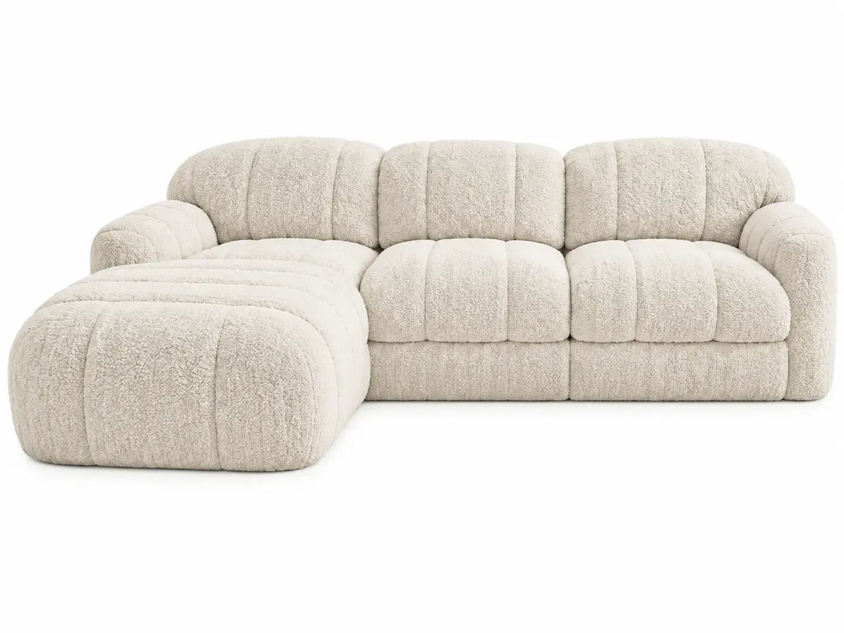 Beige L-shaped sofa with quilted cushions from Architraveandabacus, featuring plush upholstery and modern design.